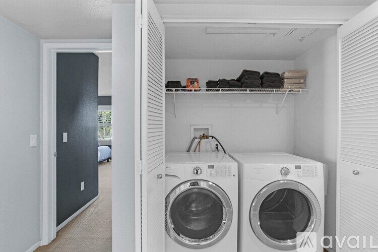 A laundry room with two washing machines and a shelf with folded towels.