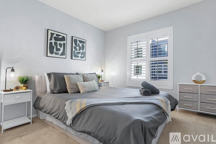 A bedroom with a bed, nightstand, and two wall art pieces.