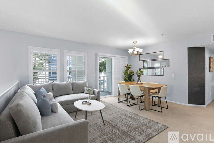 A living room with a grey couch, a white coffee table, and a dining table with chairs.