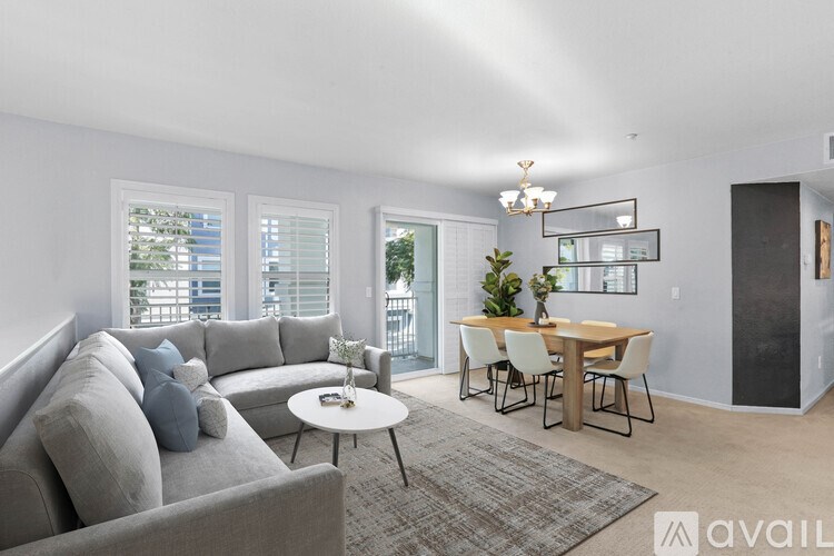 A living room with a grey couch, a white coffee table, and a dining table with chairs.