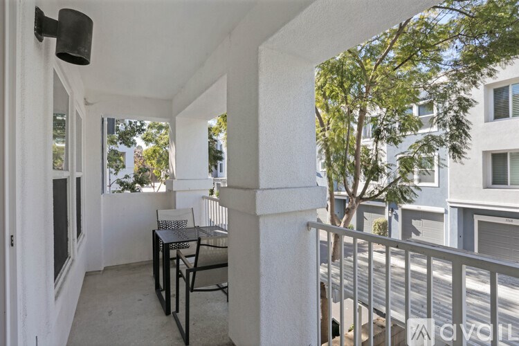 A balcony with a table and chairs overlooks a street.
