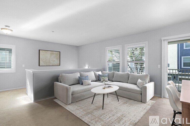A living room with a grey couch, a coffee table, and a painting on the wall.