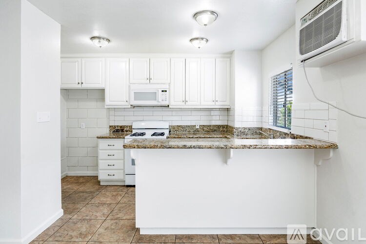 A kitchen with white cabinets and a granite countertop.