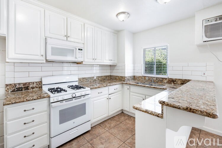 A kitchen with white cabinets and a granite countertop.
