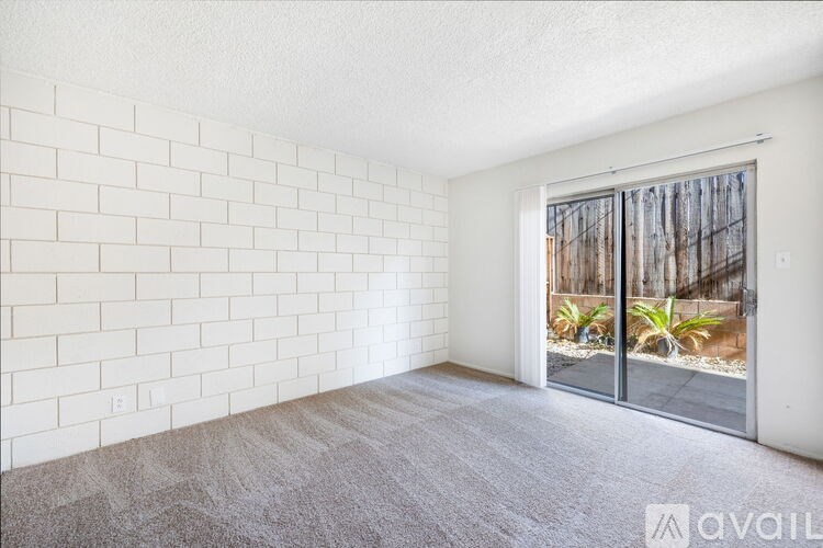 A room with a carpeted floor and a sliding glass door leading to a backyard.