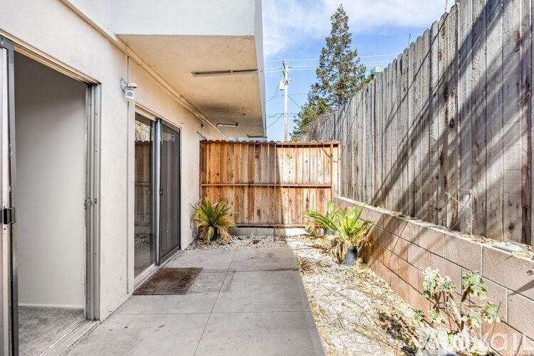 A patio area with a wooden fence and plants.