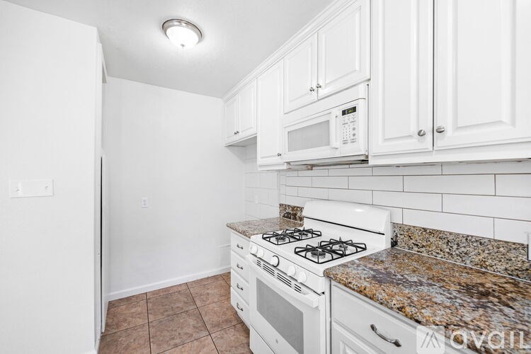 A kitchen with a white stove and cabinets.