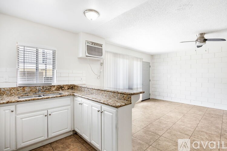 A kitchen with white cabinets and a granite countertop.