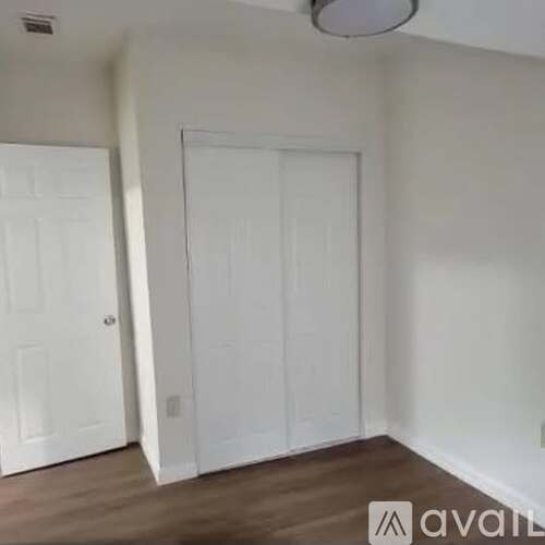 A room with two white doors and a wooden floor.