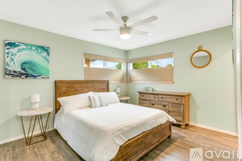 A bedroom with a bed, nightstand, and a painting of a wave on the wall.