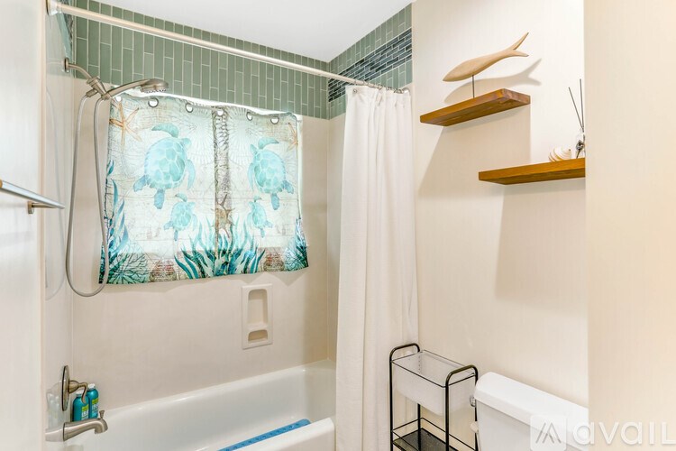 A bathroom with a white tub and a shower curtain with a blue and green design.