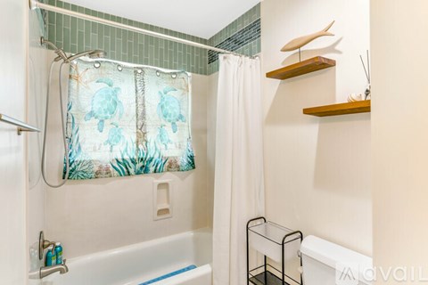A bathroom with a white tub and a shower curtain with a blue and green design.