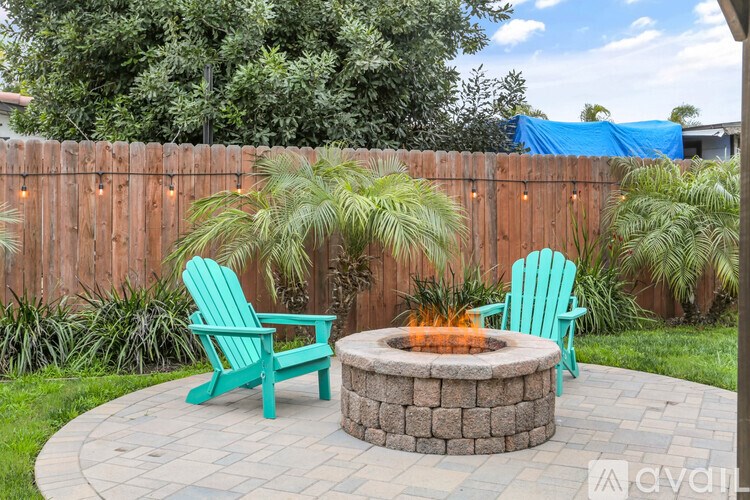 A backyard with a fire pit and two chairs.
