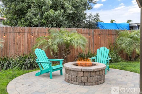 A backyard with a fire pit and two chairs.