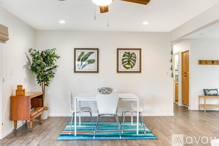 A living room with a white chair and a blue rug.