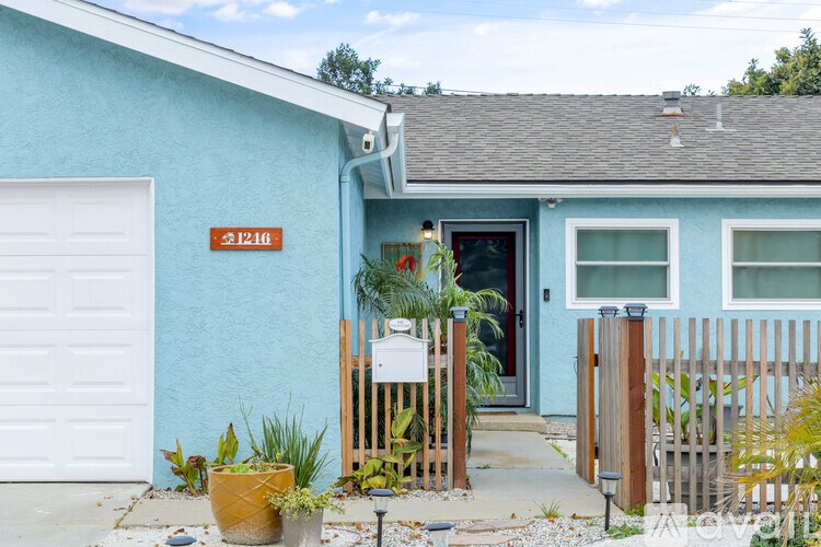 A blue house with a white garage door and a red door.