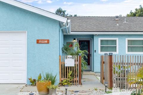 A blue house with a white garage door and a red door.