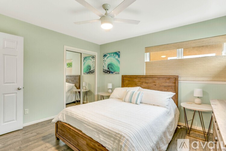 A bedroom with a bed, a ceiling fan, and a nightstand with a lamp.