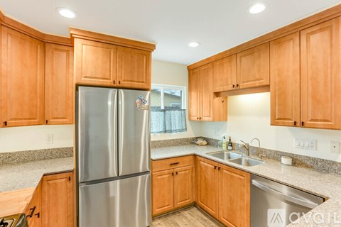 A kitchen with wooden cabinets and a stainless steel refrigerator.