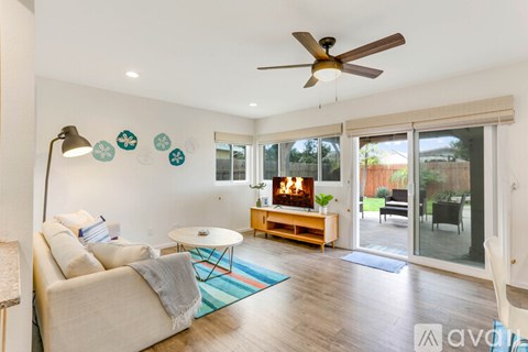 A living room with a beige couch, a round table, and a ceiling fan.