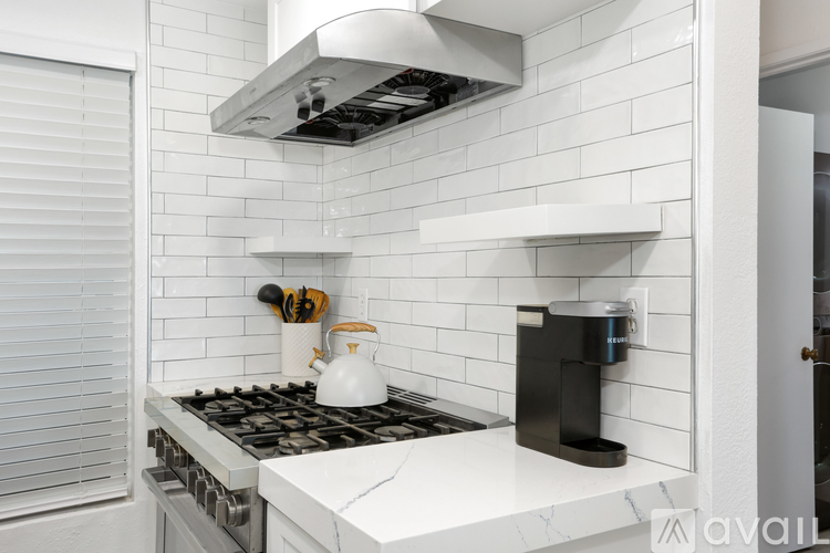 A modern kitchen with a white tiled backsplash and a white stove top.