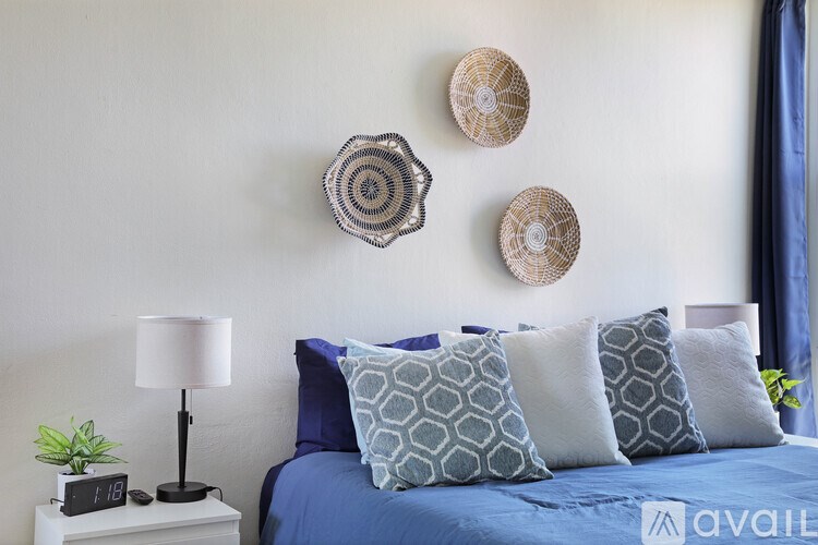 A bedroom with a bed, pillows, a lamp, and wall decorations.