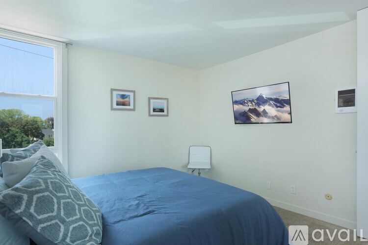 A bedroom with a blue bedspread and two pictures on the wall.