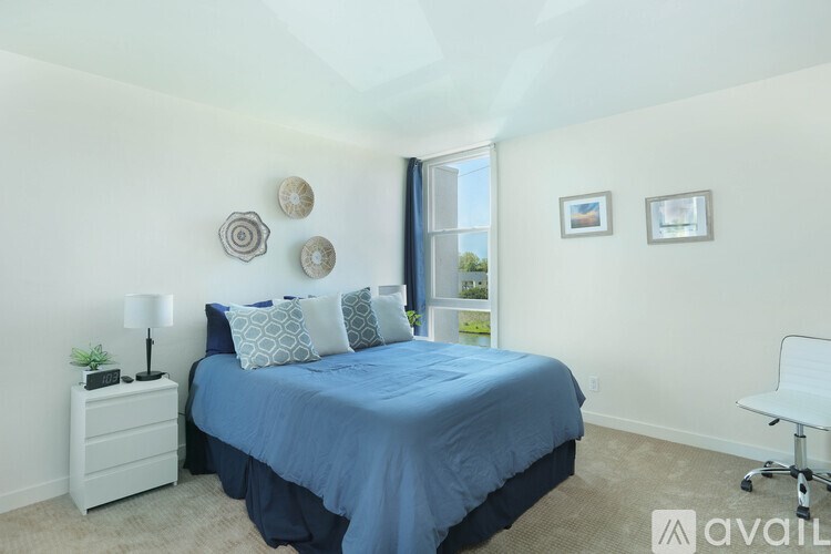 A bedroom with a blue bedspread and a white chair.