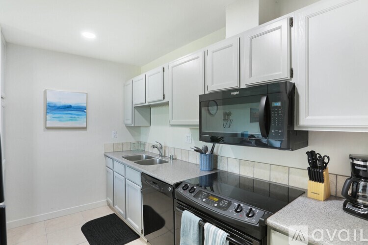 A kitchen with white cabinets and a black microwave.