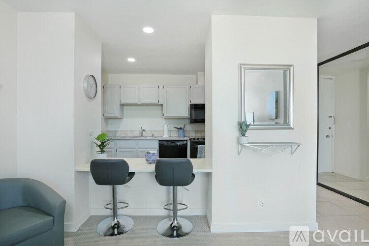 A kitchen with white cabinets and a bar area with two stools.
