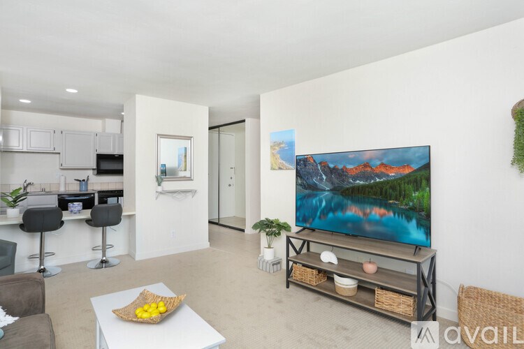 A modern living room with a large flat screen TV and a kitchen area.