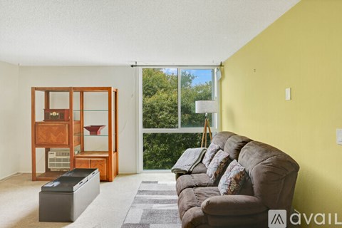 A living room with a brown couch and a wooden cabinet.