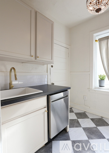 A kitchen with white cabinets and a black counter top.
