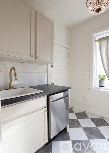 A kitchen with white cabinets and a black counter top.