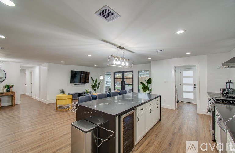 A modern kitchen with wooden floors and stainless steel appliances.