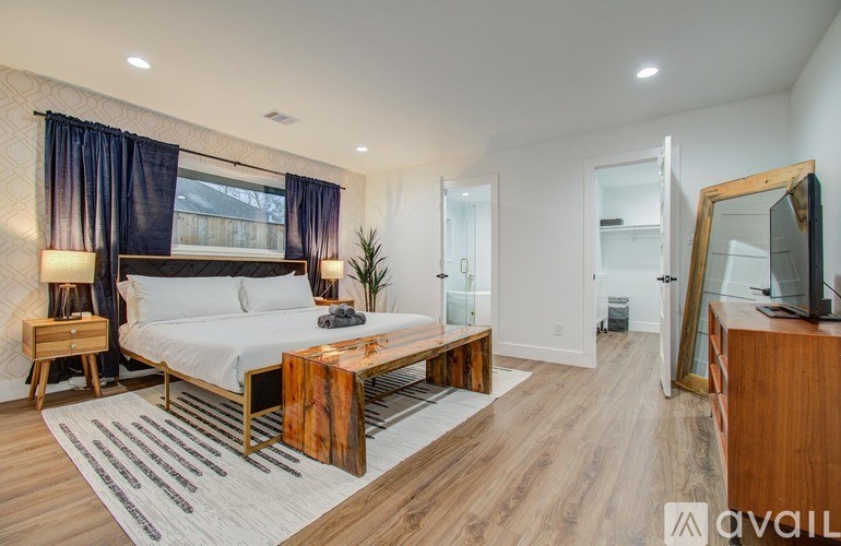 A bedroom with a bed, nightstand, and a wooden coffee table.