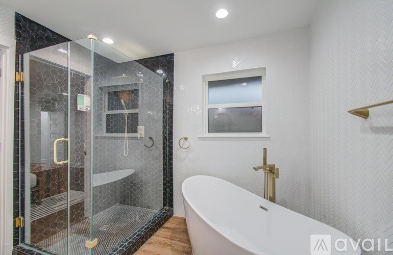 A modern bathroom with a glass shower stall and a white bathtub.