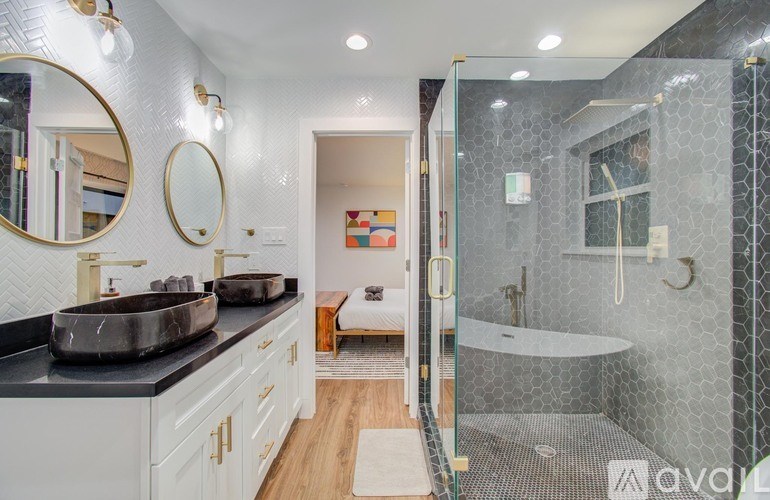 A bathroom with a glass shower stall and a sink with a black counter.