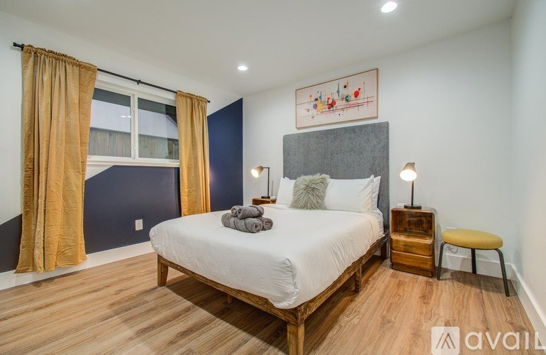 A bedroom with a bed, nightstands, and a window with curtains.