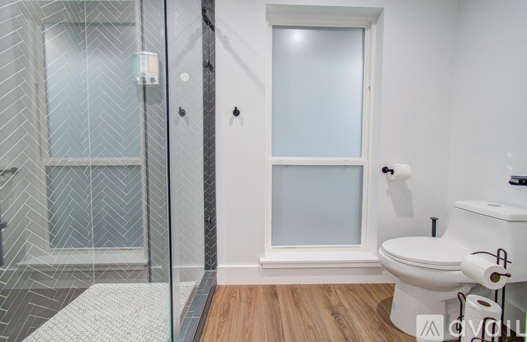 A white toilet sits next to a glass shower door in a bathroom.