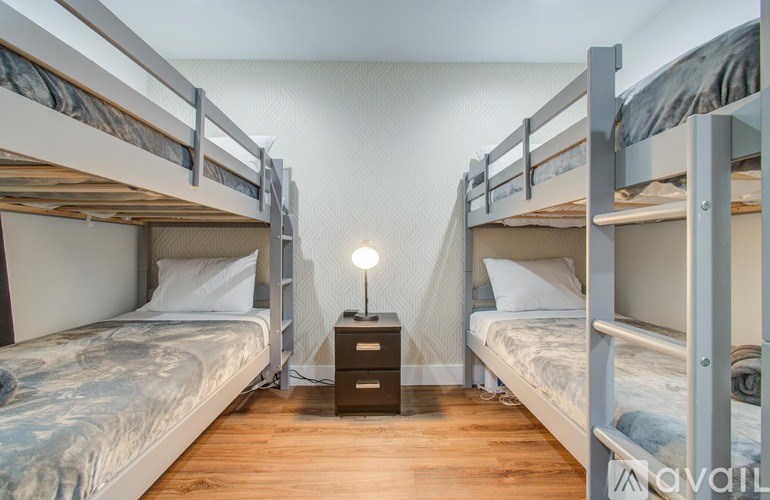 A room with two bunk beds and a nightstand with a lamp.