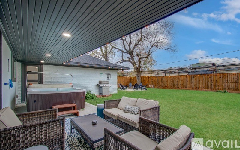 A backyard with a hot tub, patio furniture, and a wooden fence.