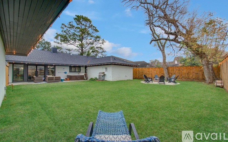A backyard with a lawn and a blue chair.