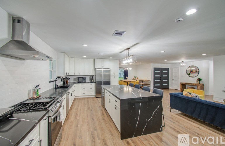 A modern kitchen with a black countertop and stainless steel appliances.