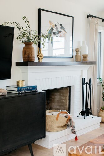 A black TV sits on a stand in front of a white fireplace.