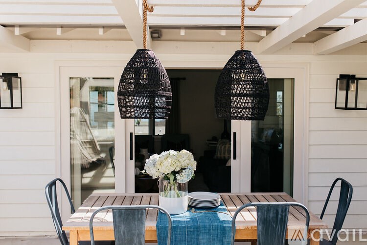 A table with a vase of flowers and two hanging lamps.
