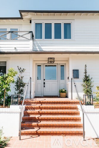A white house with a grey roof and a white fence.