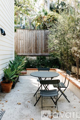 A patio with a table and chairs surrounded by greenery.