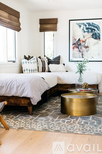 A bedroom with a bed, a bench, and a painting on the wall.