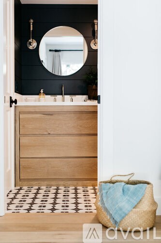 A bathroom with a wooden vanity and a round mirror above it.
